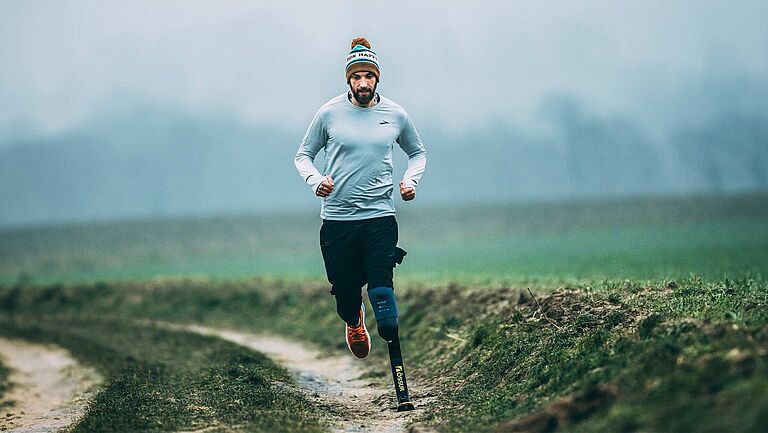 Triathlet Kim Cremer, mit amputiertem linken Unterschenkel, läuft über einen Feldweg