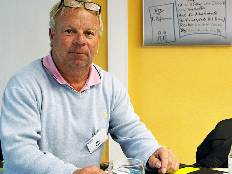 Jörg Eilers, Sifa der Lübecker Hafen-Gesellschaft, sitzt am einem Tisch und Schaut in die Kamera. 