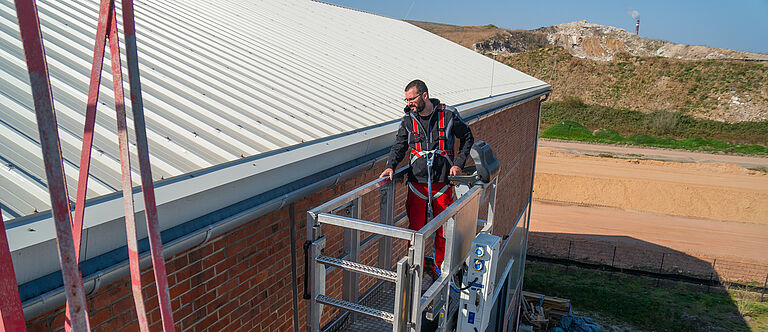 Die sichere fahrbare Hubarbeitsbühne Ein Mann steht gesichert auf einer fahrbaren Hubarbeitsbühne.