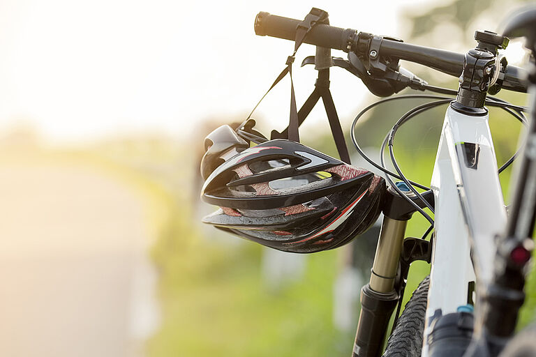 Ein Helm hängt im Sonnenschein am Fahrradlenker