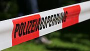 Nahaufnahme eines rot-weißen Bandes mit der Aufschrift "Polizeiabsperrung"