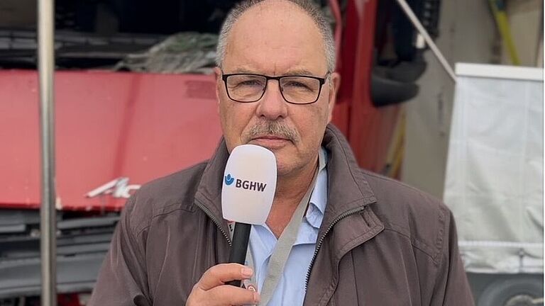 Dieter Schäfer mit Mikrofon in der Hand vor dem LKW-Exponat